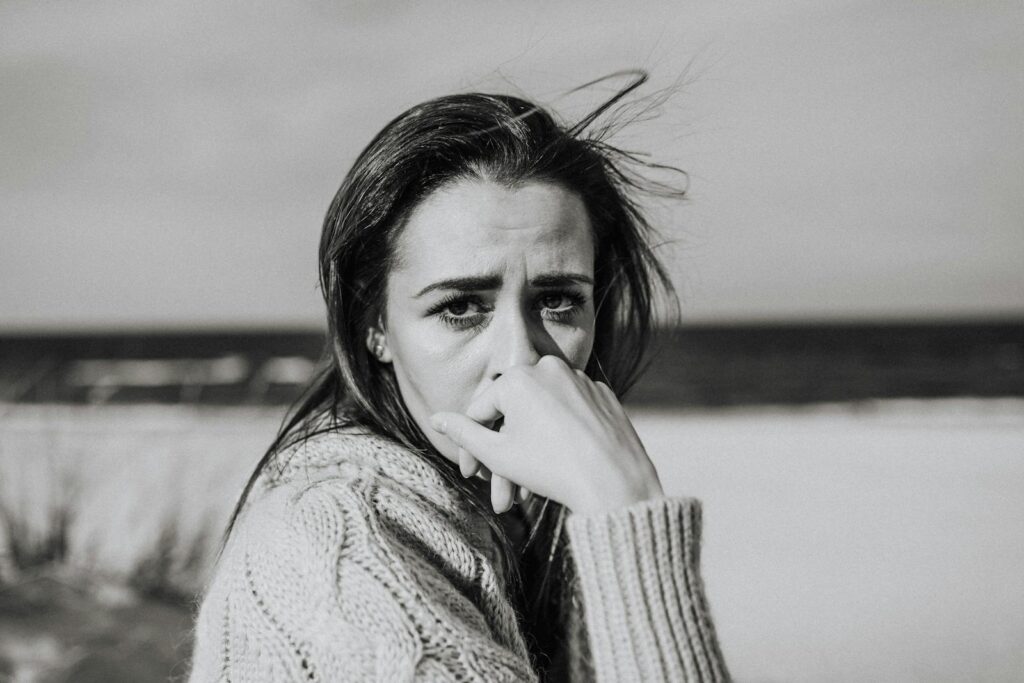 A monochrome portrait of a woman with pensive expression at the beach.